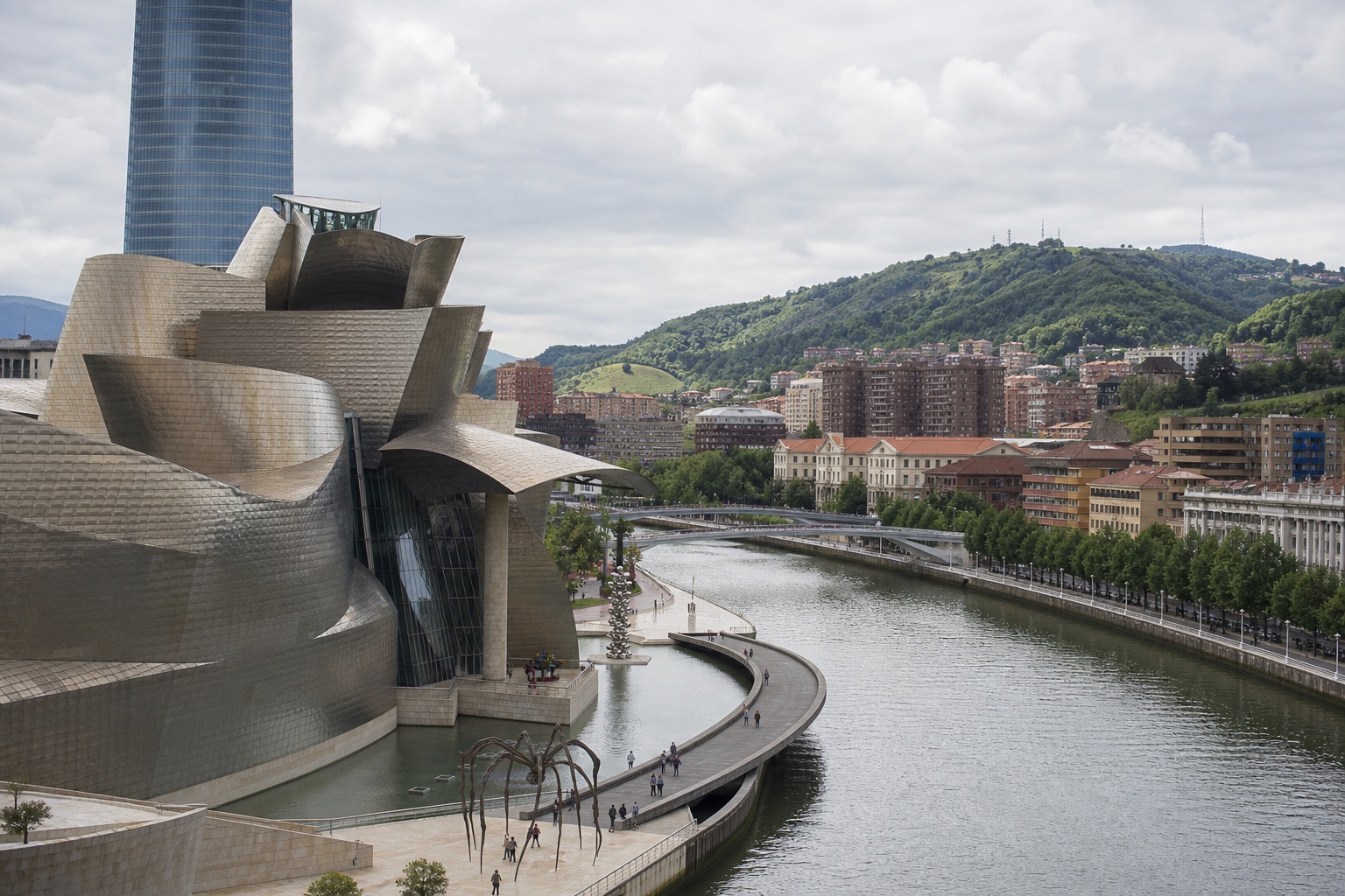 The Guggenheim Museum Bilbao beside the Nervión river and city bridges in clear daylight