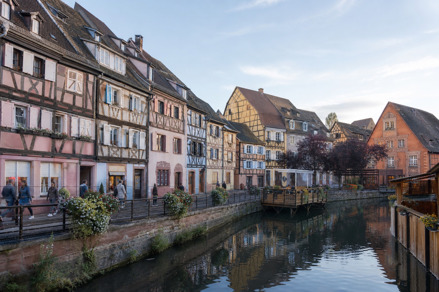 Colmar canal lined by colorful half-timbered houses and ordinary morning pedestrians