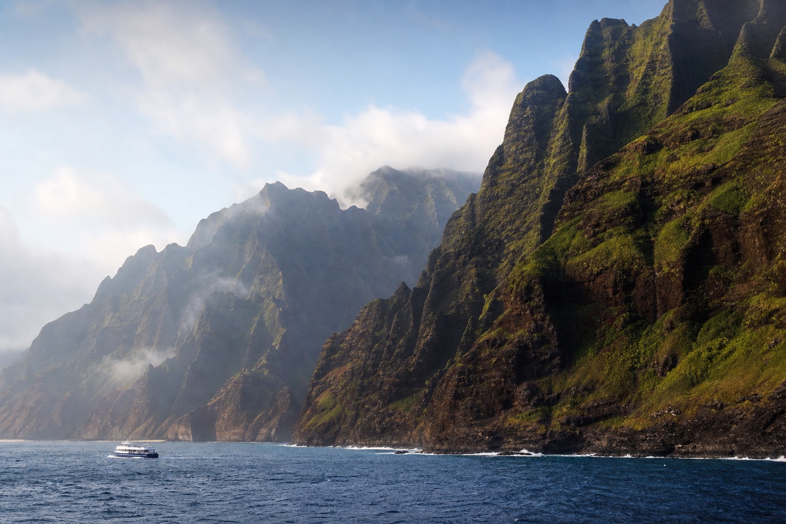 The steep green folds of Kauaʻi's Nā Pali Coast rising above the Pacific in soft morning light