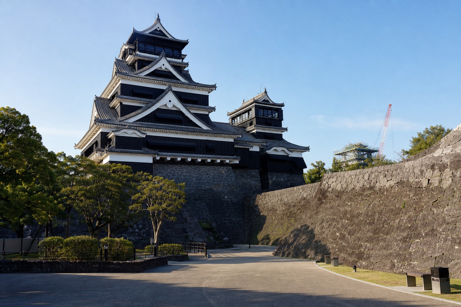Kumamoto Castle's dark keep and curved stone walls with visible restoration work in clear morning light