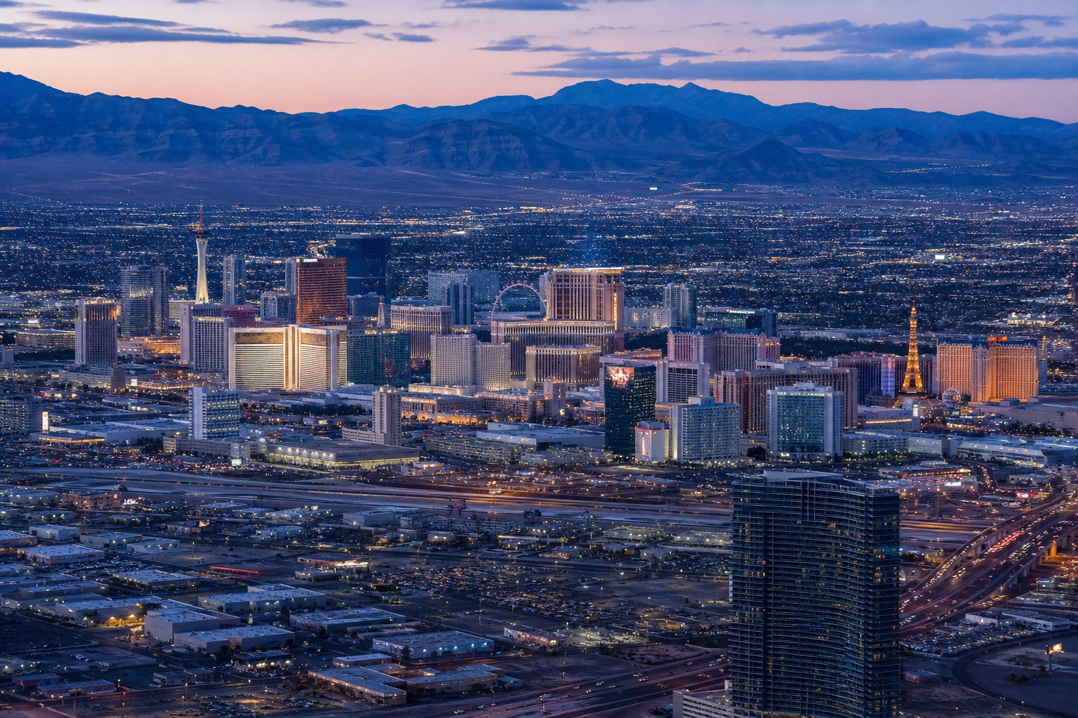 The Las Vegas Strip glowing at blue hour within its broad desert basin and mountain horizon