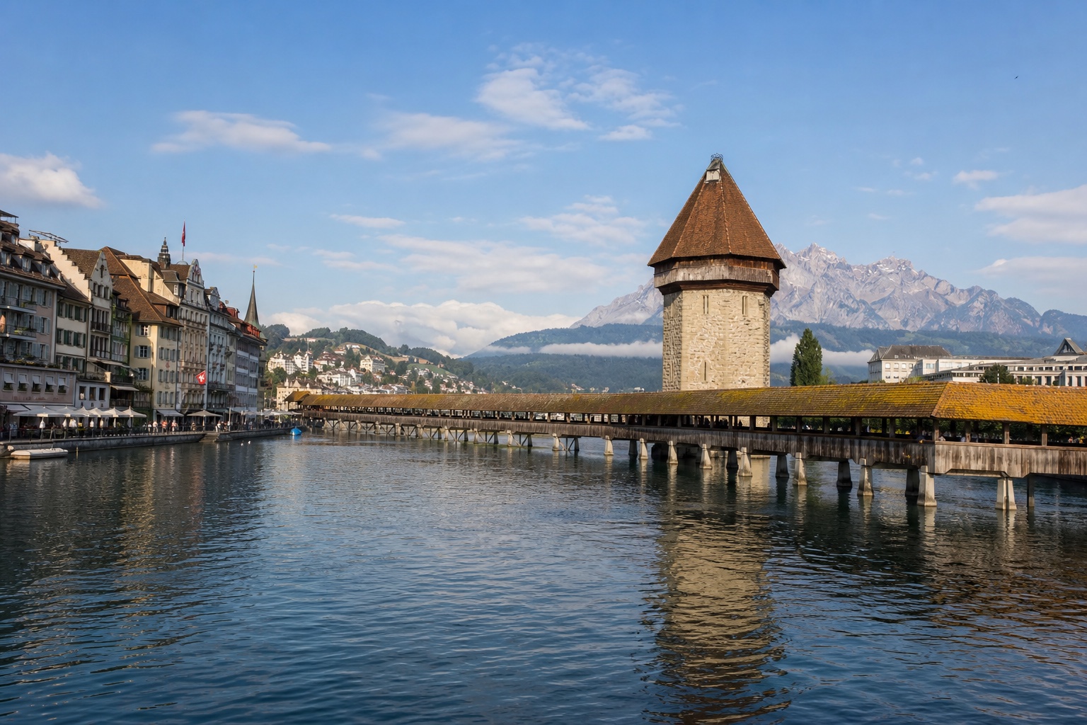 Lucerne's Chapel Bridge, old town, river, and mountain backdrop in clear light