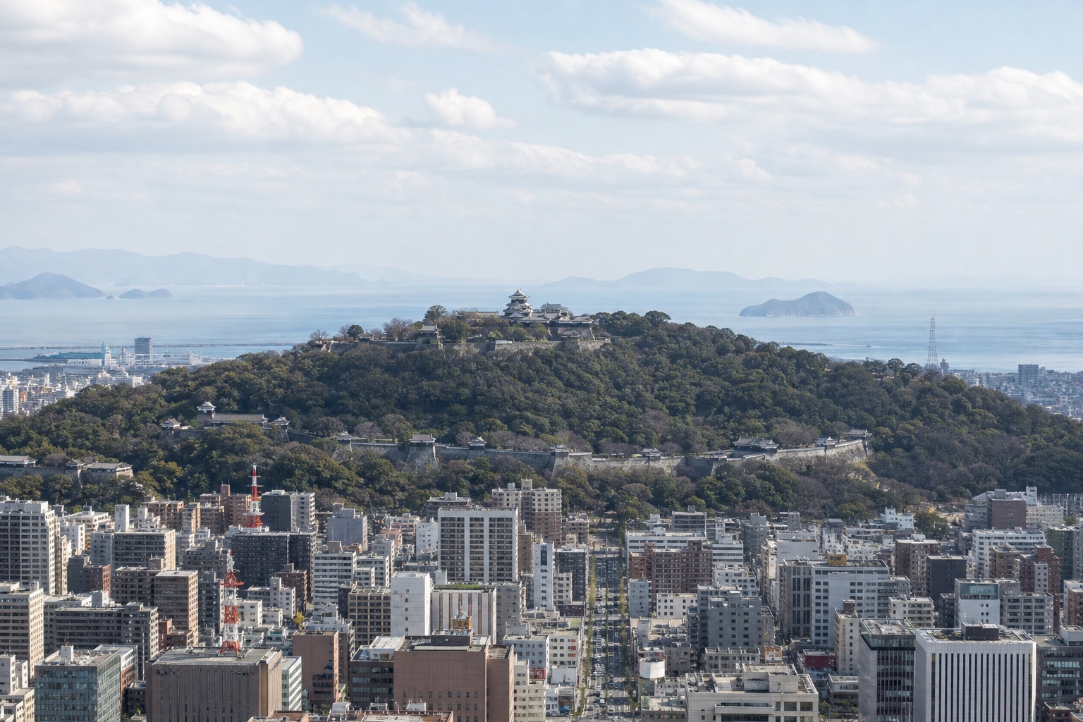 Matsuyama Castle rising above the city with the Seto Inland Sea visible beyond