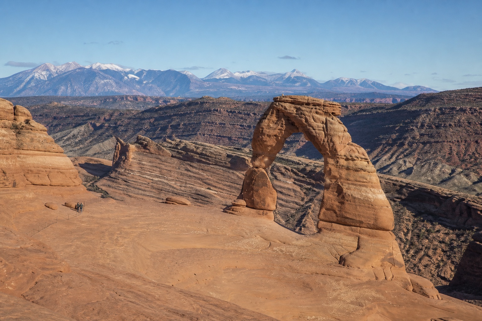 A natural sandstone arch near Moab with the Colorado Plateau and snow-dusted La Sal Mountains beyond