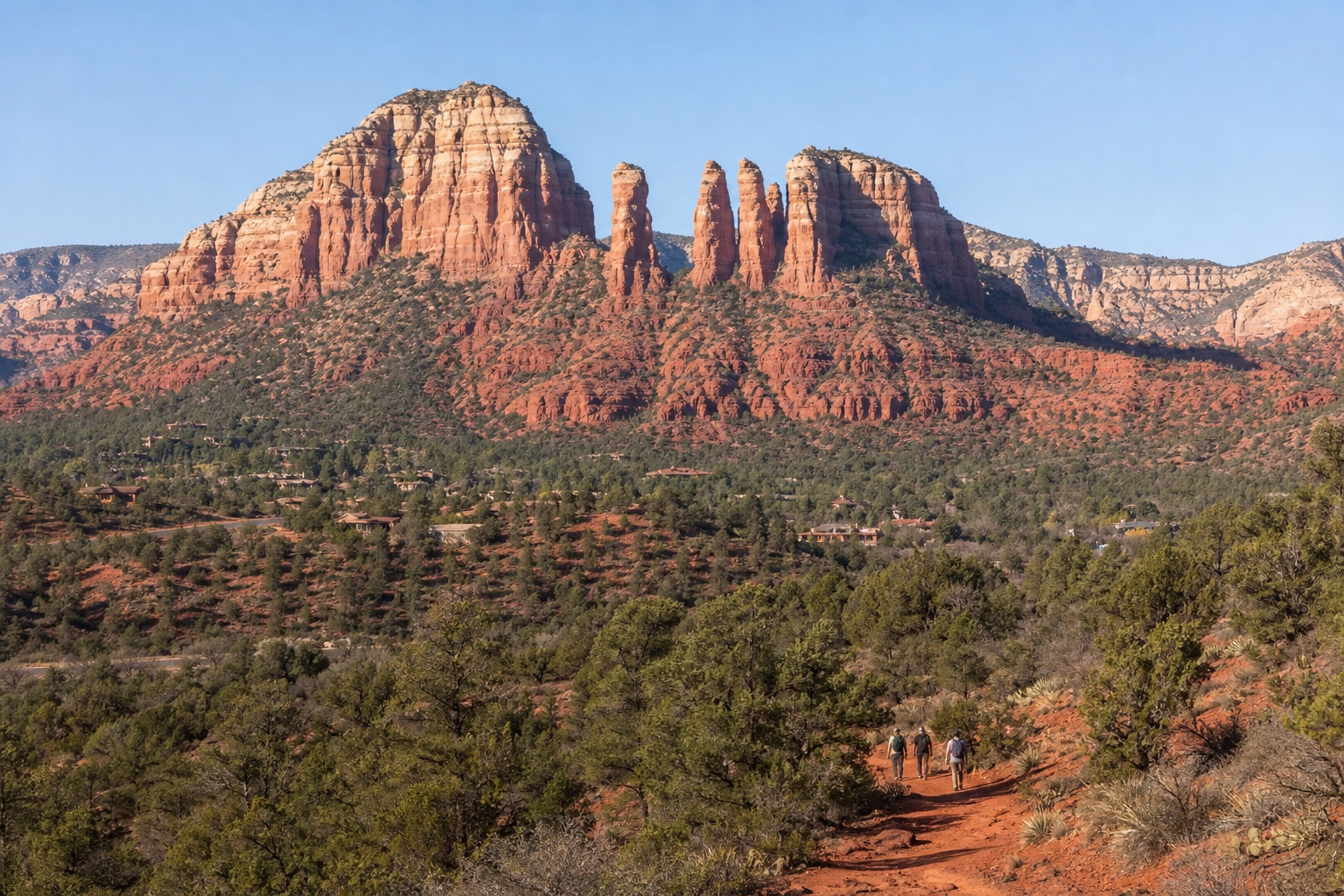 Sedona red-rock formations above desert vegetation and a maintained trail in clear morning light
